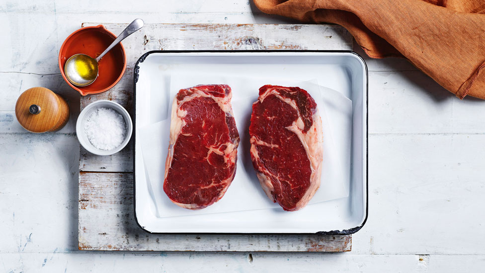 Two uncooked steaks in a baking dish