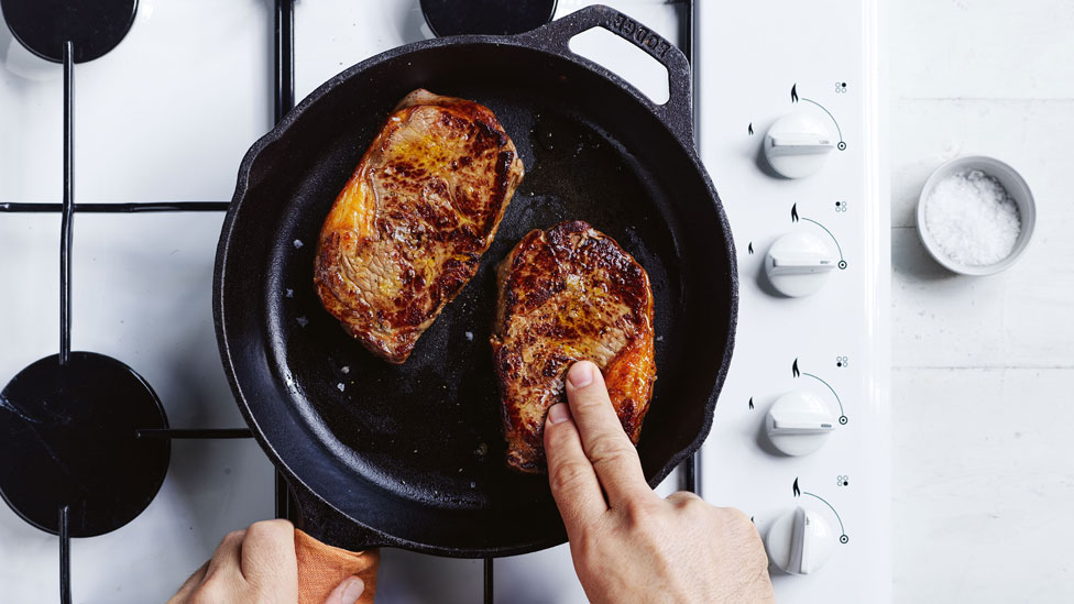 Two steaks being cooked in a pan