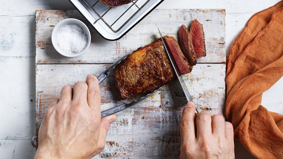 A person cutting steak into slices
