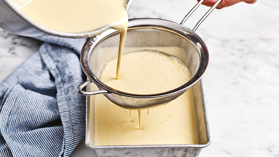 Filtering lumpy bits out of the custard with a sieve