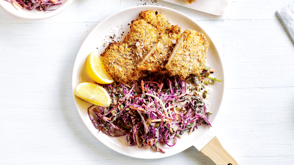 Crumbed chicken, coleslaw and lemon wedges on a plate