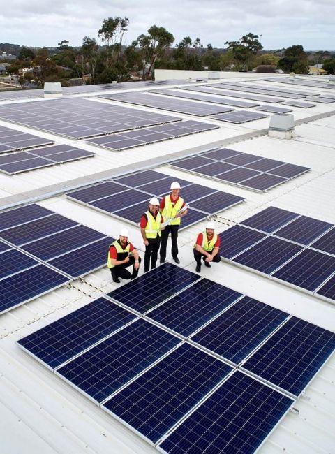 Coles team members inspecting solar panels on the roof of a Coles supermarket in Drysdale, Victoria