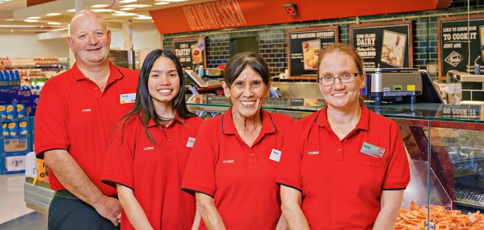 Four Coles employees smiling at camera
