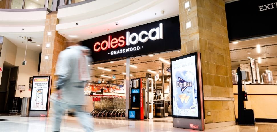 Person walking past the storefront of Coles Local Chatswood