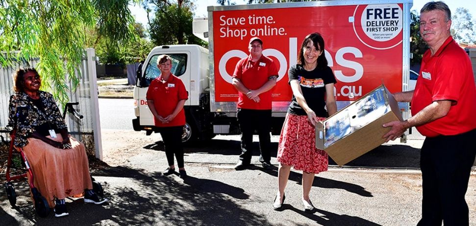 Coles team members with indigenous lady smiling as Coles delivers groceries to community in need