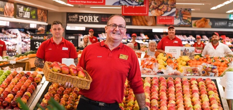 Regional manager John Appleby holding a tray of apples in a coles store
