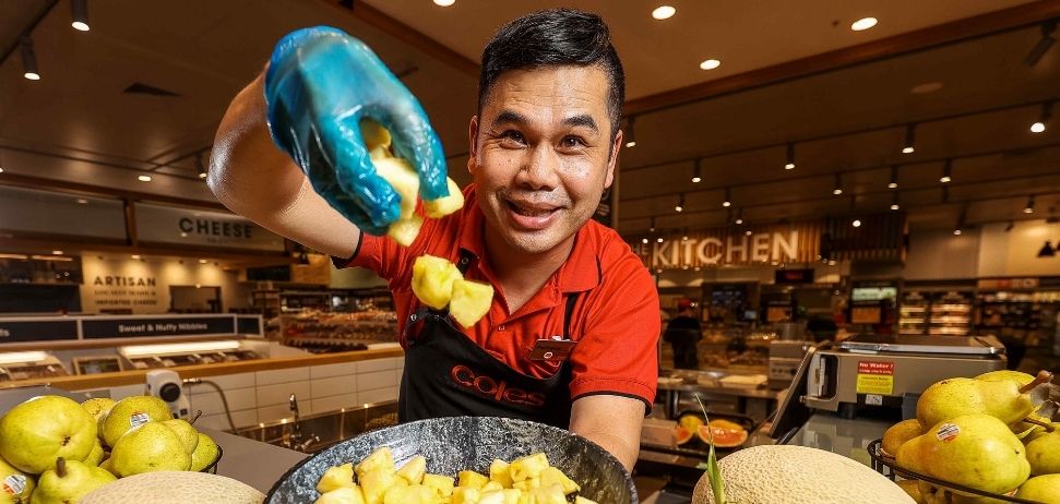 Coles employee dropping cut pineapple into bowl at Coles Moonee Ponds fruit and vegetable bar