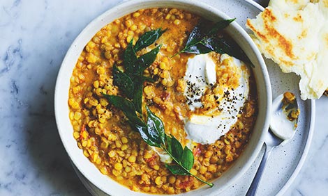 A bowl of legume soup topped with herbs and sour cream
