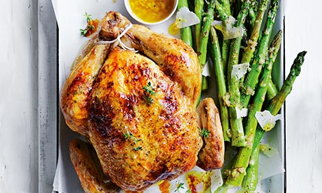 A whole roast chicken with asparagus on the side